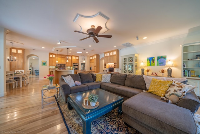 living room featuring ceiling fan with notable chandelier, light wood-type flooring, and ornamental molding