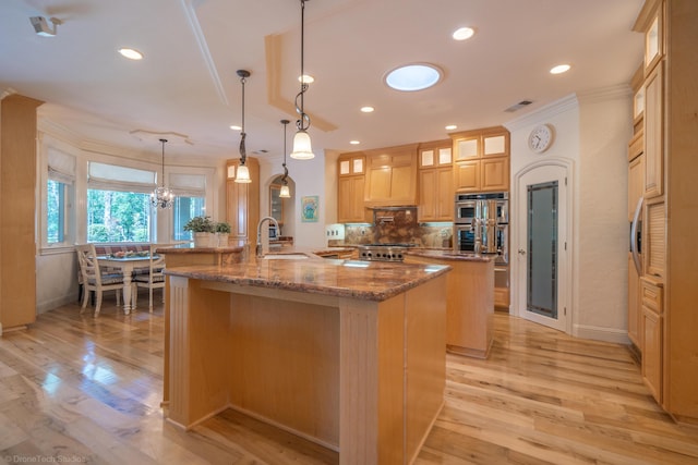 kitchen featuring a large island, sink, light stone counters, pendant lighting, and custom exhaust hood