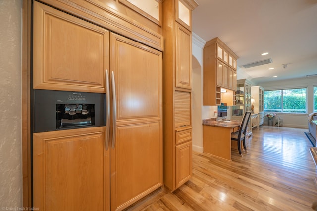 kitchen featuring paneled refrigerator, light wood-type flooring, and built in desk