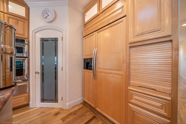 kitchen featuring light wood-type flooring, double oven, and crown molding