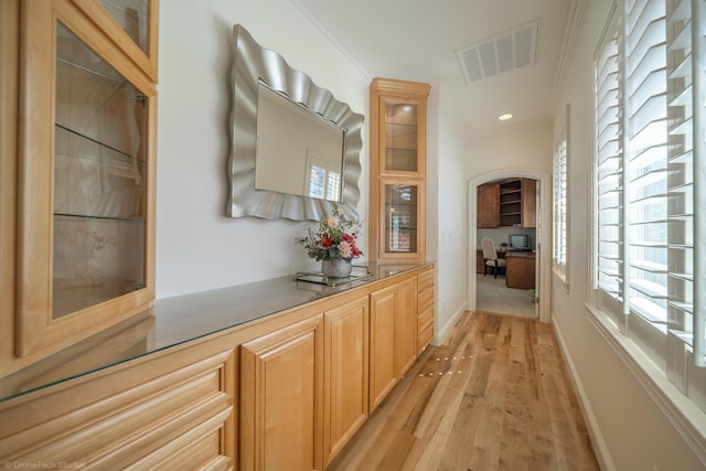 corridor featuring crown molding, plenty of natural light, and light hardwood / wood-style floors