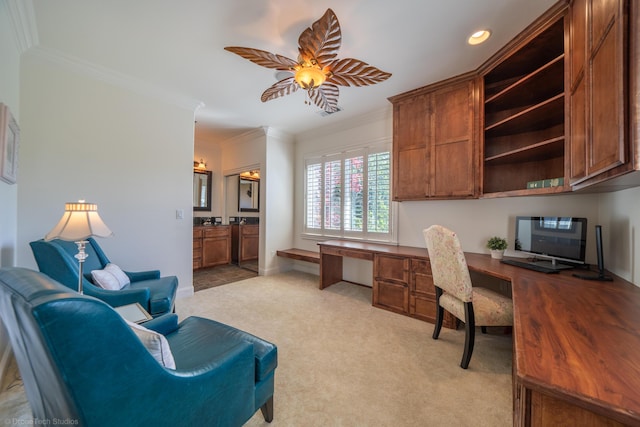 carpeted office with ceiling fan, built in desk, and crown molding