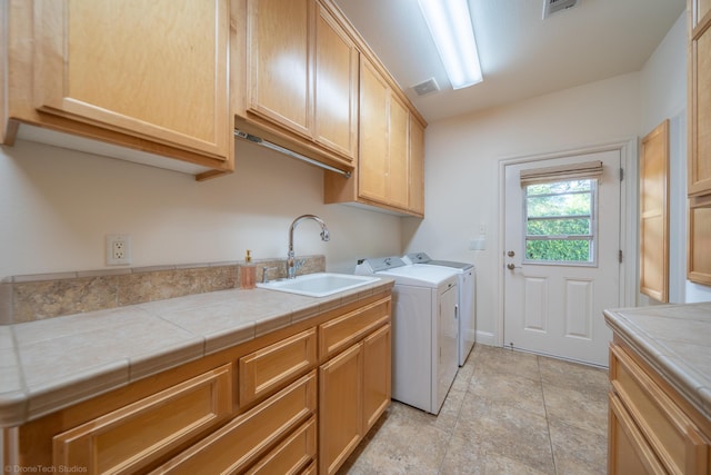 washroom with cabinets, independent washer and dryer, and sink