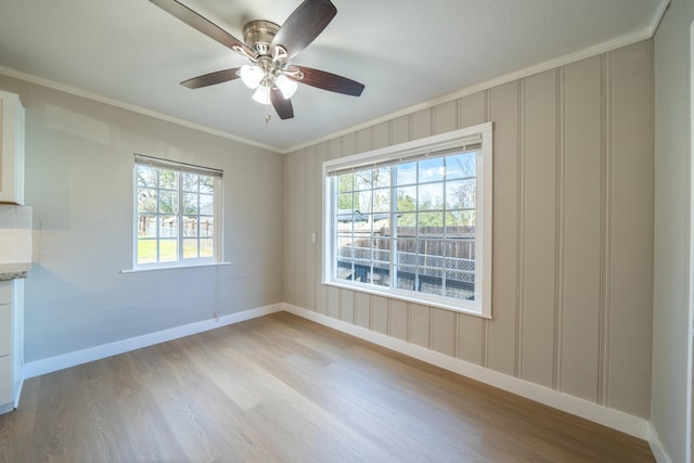 spare room featuring crown molding, ceiling fan, and light wood-type flooring