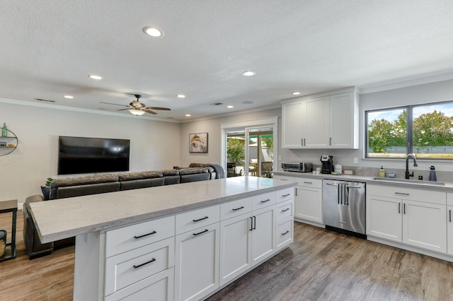 kitchen with stainless steel dishwasher, ceiling fan, sink, and white cabinetry