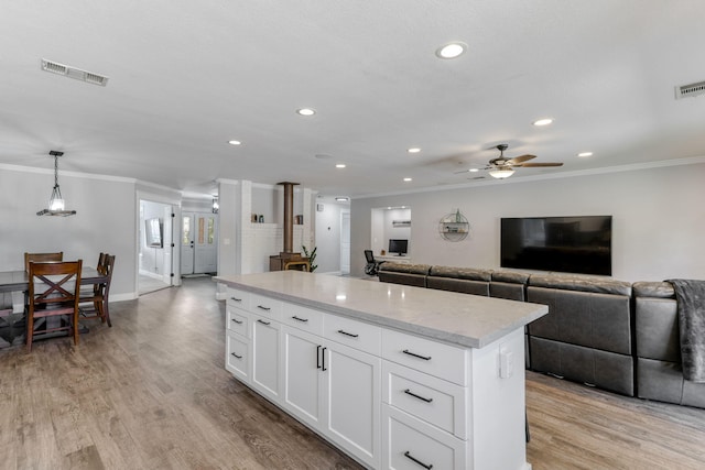 kitchen featuring white cabinetry, ceiling fan, light wood-type flooring, hanging light fixtures, and a kitchen island