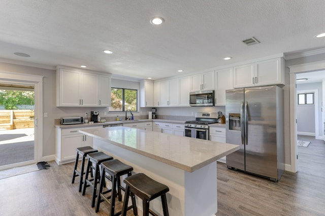 kitchen featuring sink, appliances with stainless steel finishes, a kitchen breakfast bar, and white cabinetry