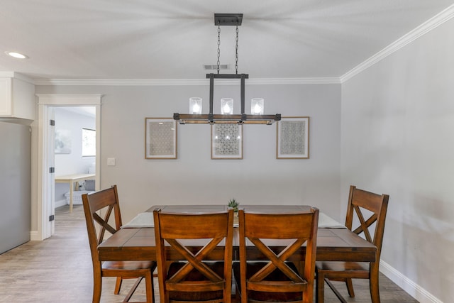 dining area featuring light hardwood / wood-style floors, crown molding, and a notable chandelier