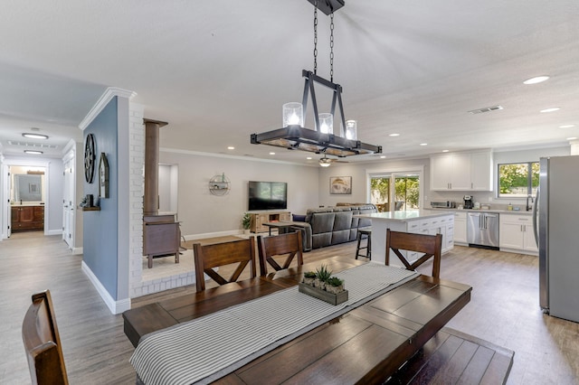 dining area with ornamental molding and light hardwood / wood-style flooring