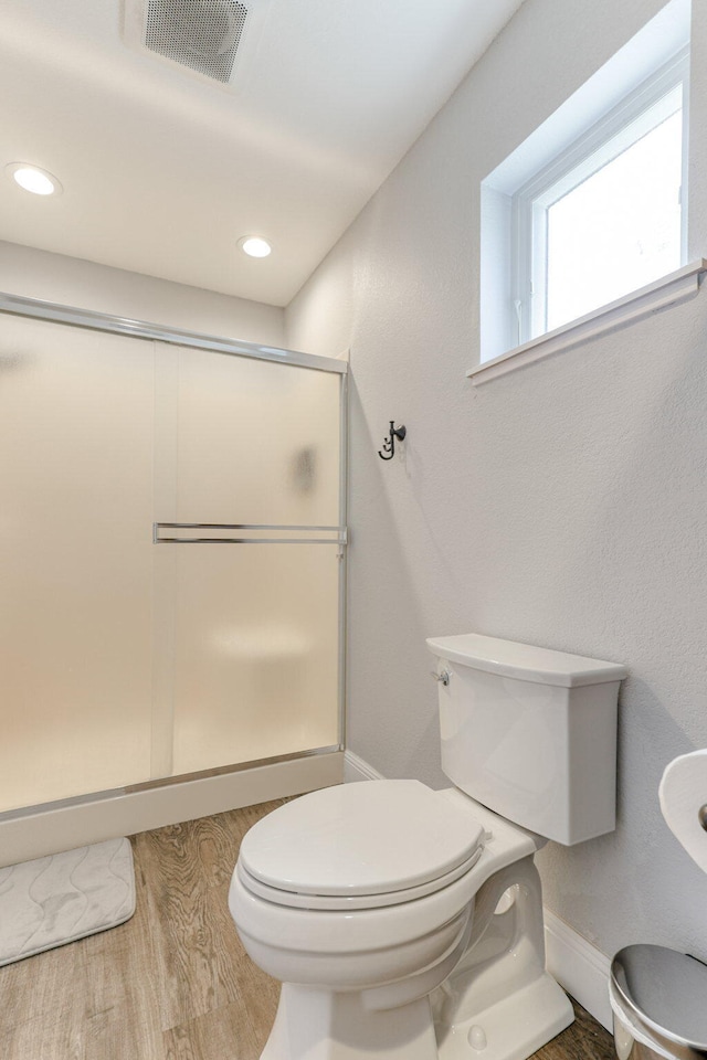 bathroom with wood-type flooring, an enclosed shower, and toilet