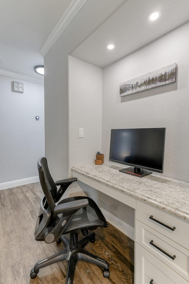 office space featuring built in desk, crown molding, and light hardwood / wood-style floors