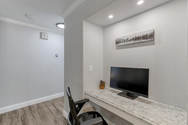 office space featuring built in desk, crown molding, and light hardwood / wood-style flooring