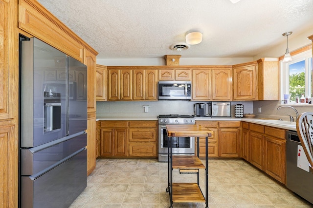 kitchen featuring pendant lighting, stainless steel appliances, and sink