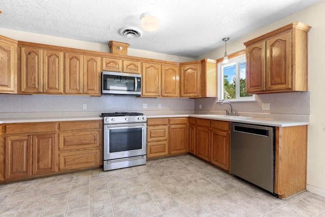 2048 Wilder Dr, Redding, CA 96001 - kitchen featuring stainless steel appliances, light countertops, brown cabinetry, a textured ceiling, and pendant lighting