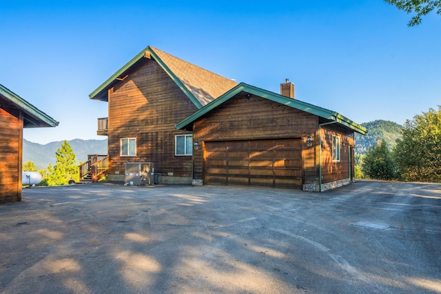 view of side of home with a mountain view and a garage