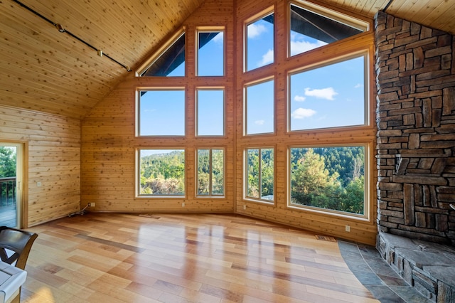 unfurnished living room featuring wooden walls, wooden ceiling, track lighting, and light hardwood / wood-style floors