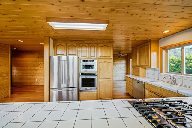 kitchen featuring decorative backsplash, stainless steel appliances, sink, tile countertops, and wooden ceiling