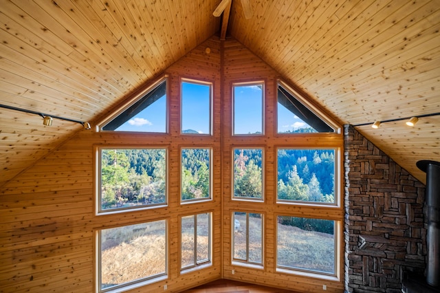 interior space with wooden ceiling, a wood stove, high vaulted ceiling, wooden walls, and beamed ceiling