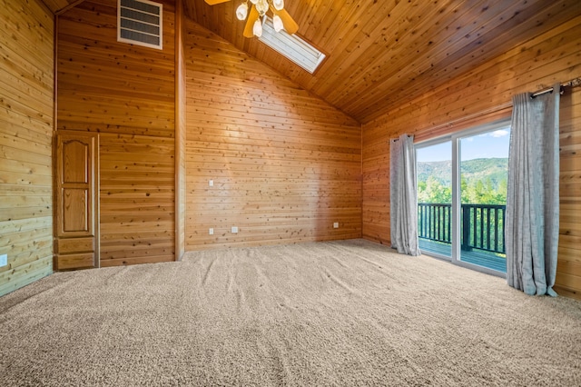 unfurnished room featuring a skylight, a mountain view, wooden walls, and high vaulted ceiling