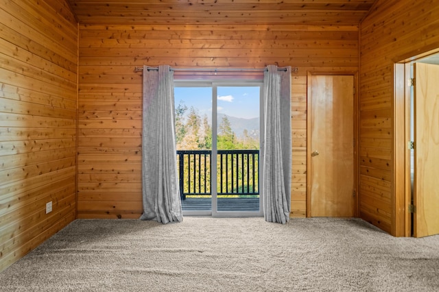 carpeted spare room featuring wooden walls, a mountain view, and lofted ceiling