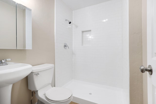 bathroom with toilet and a tile shower