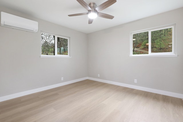 unfurnished room featuring a wall mounted air conditioner, ceiling fan, and light wood-type flooring