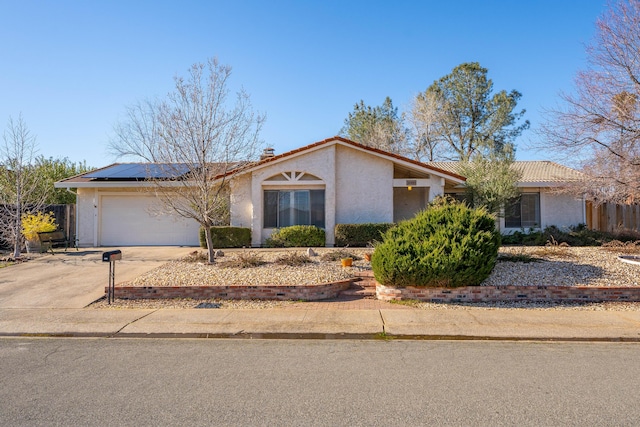 single story home with a garage and solar panels