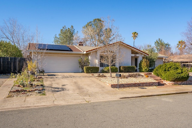 ranch-style home featuring a garage and solar panels