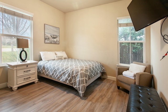 bedroom with multiple windows and light wood-type flooring