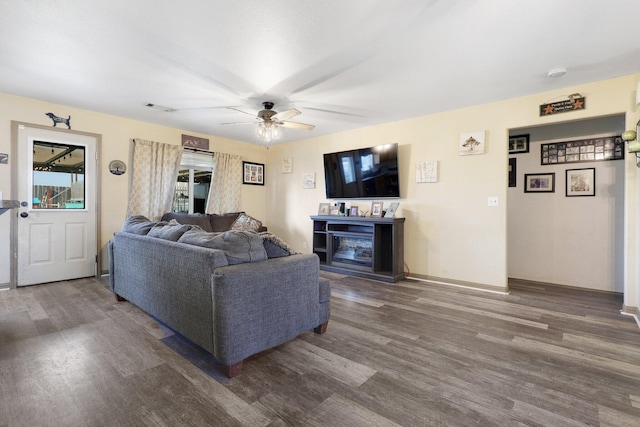 living room featuring ceiling fan, dark hardwood / wood-style floors, and a fireplace