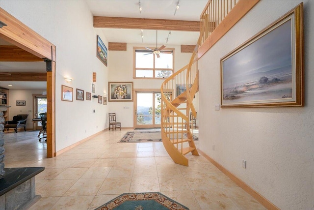 foyer entrance with rail lighting, ceiling fan, a towering ceiling, light tile patterned floors, and beam ceiling