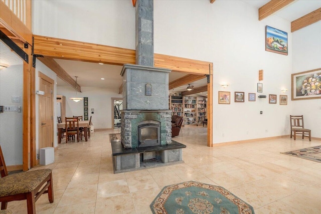 living room with beam ceiling, light tile patterned flooring, a towering ceiling, and a wood stove