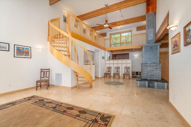 interior space with beam ceiling, ceiling fan, and a towering ceiling