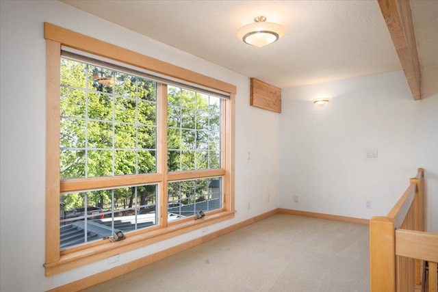 empty room with carpet and beamed ceiling