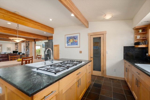 kitchen with a kitchen island with sink, light brown cabinets, beamed ceiling, and stainless steel gas cooktop