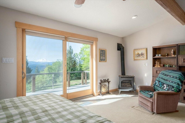 bedroom featuring light carpet, access to outside, vaulted ceiling, ceiling fan, and a wood stove