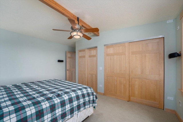 bedroom with light carpet, vaulted ceiling, ceiling fan, a textured ceiling, and multiple closets