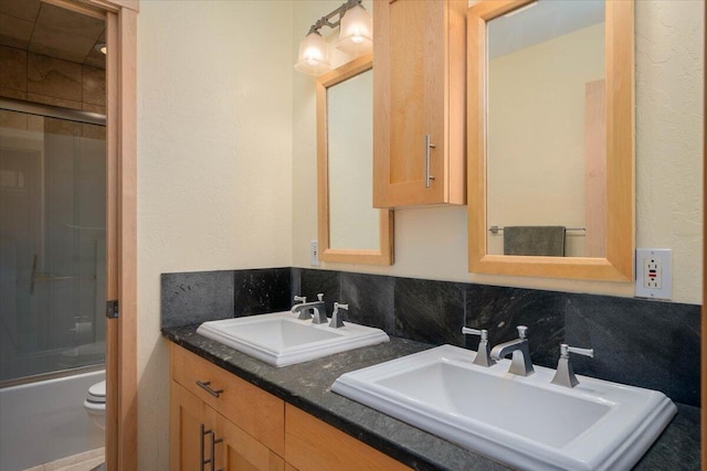 full bathroom with vanity, toilet, bath / shower combo with glass door, and tasteful backsplash