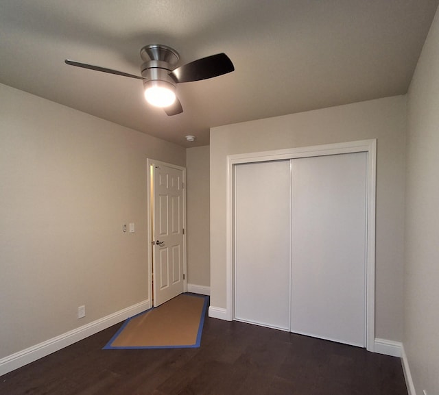 unfurnished bedroom with ceiling fan, dark wood-type flooring, and a closet