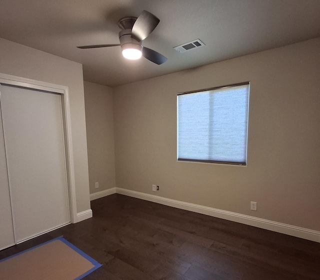 unfurnished bedroom with ceiling fan, dark hardwood / wood-style flooring, and a closet