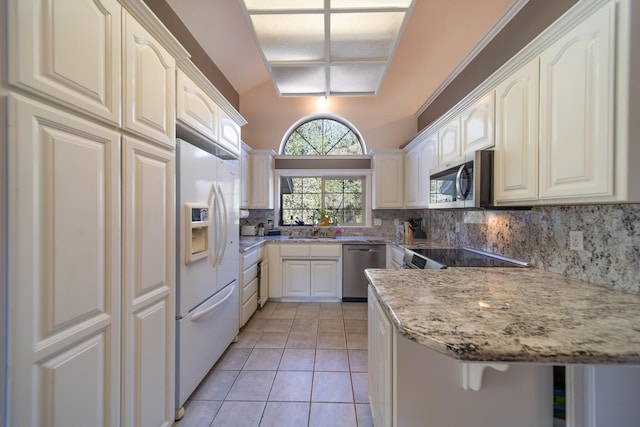 kitchen with lofted ceiling, sink, stainless steel appliances, light stone counters, and kitchen peninsula