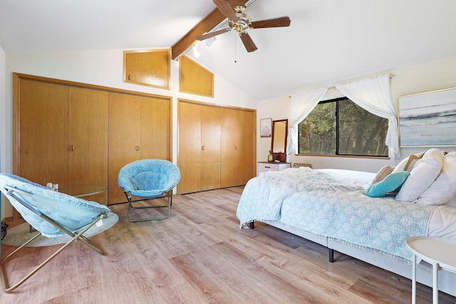 bedroom featuring ceiling fan, multiple closets, light hardwood / wood-style flooring, and vaulted ceiling with beams