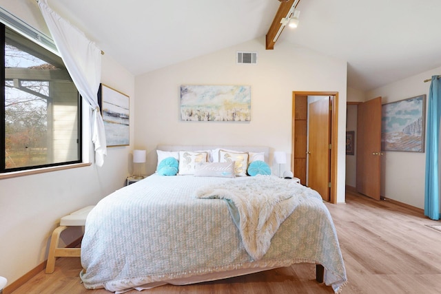 bedroom with light wood-type flooring and lofted ceiling with beams