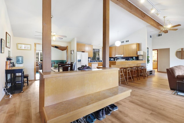 living room with light hardwood / wood-style floors, rail lighting, high vaulted ceiling, and beam ceiling