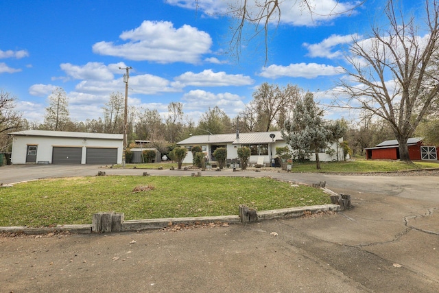 view of front of home featuring a front lawn, a garage, and an outdoor structure