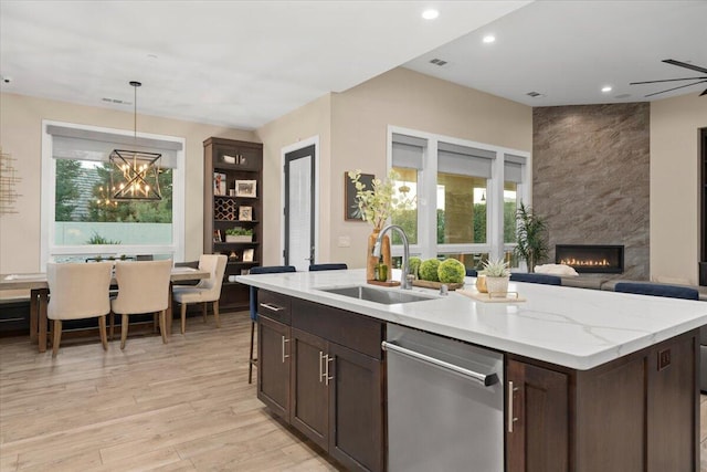 kitchen with dishwasher, a fireplace, pendant lighting, sink, and dark brown cabinetry