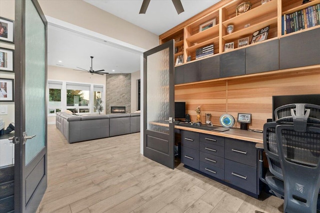 office space featuring french doors, a stone fireplace, and light hardwood / wood-style floors