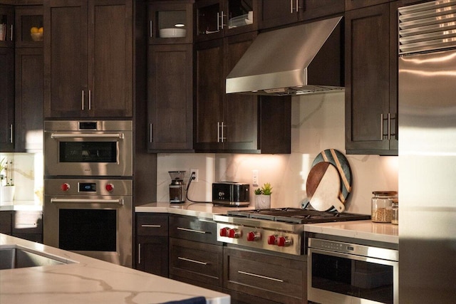 kitchen with dark brown cabinetry, wall chimney exhaust hood, and stainless steel appliances