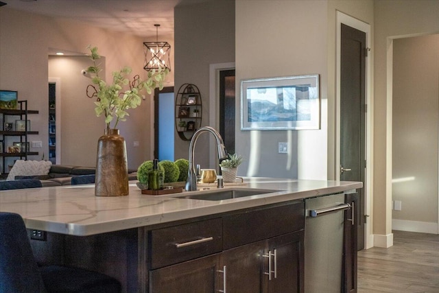 kitchen with light hardwood / wood-style floors, decorative light fixtures, stainless steel dishwasher, dark brown cabinetry, and sink