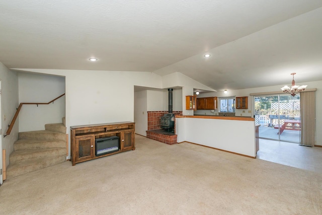 unfurnished living room featuring a wood stove, light carpet, and a chandelier